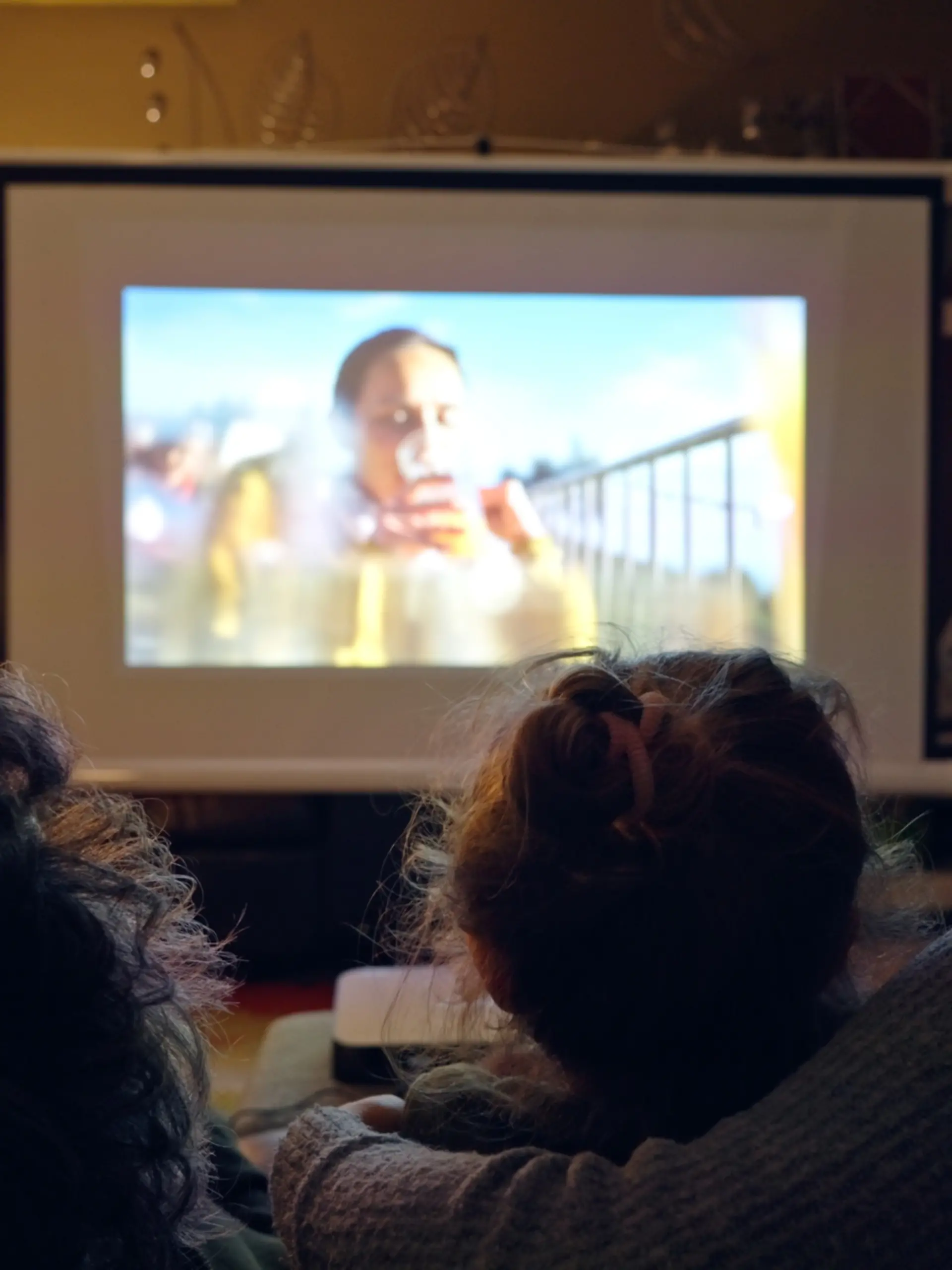 Familie sitzt auf der Couch und guckt einen Film über einen Beamer.