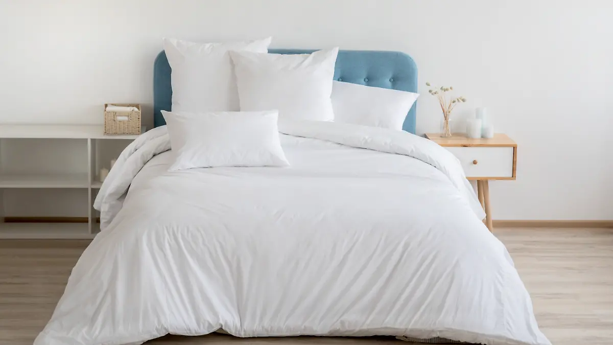 Schlafzimmer mit Bett, weißer Bettwäsche und Nachttisch.