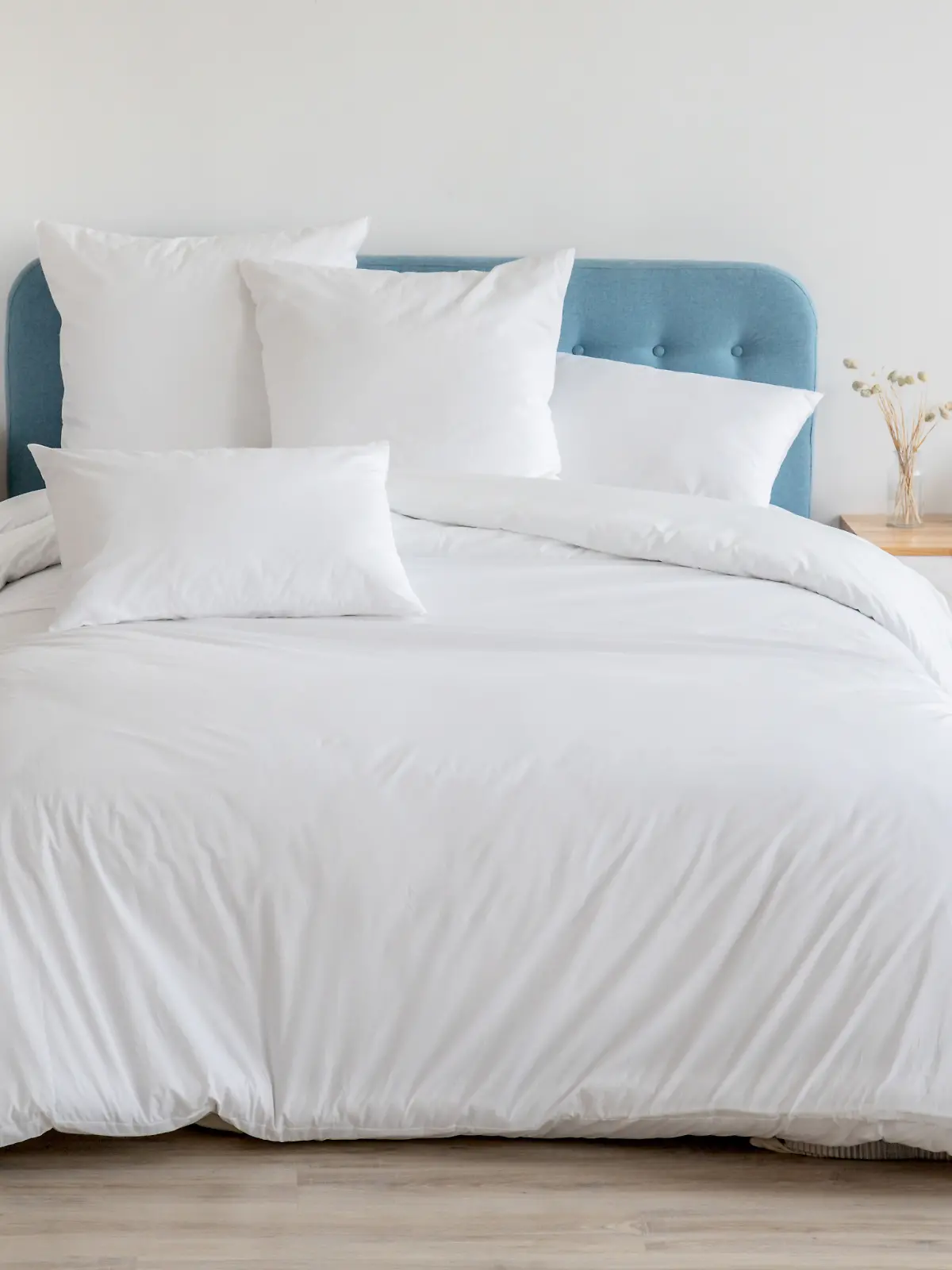 Schlafzimmer mit Bett, weißer Bettwäsche und Nachttisch. 