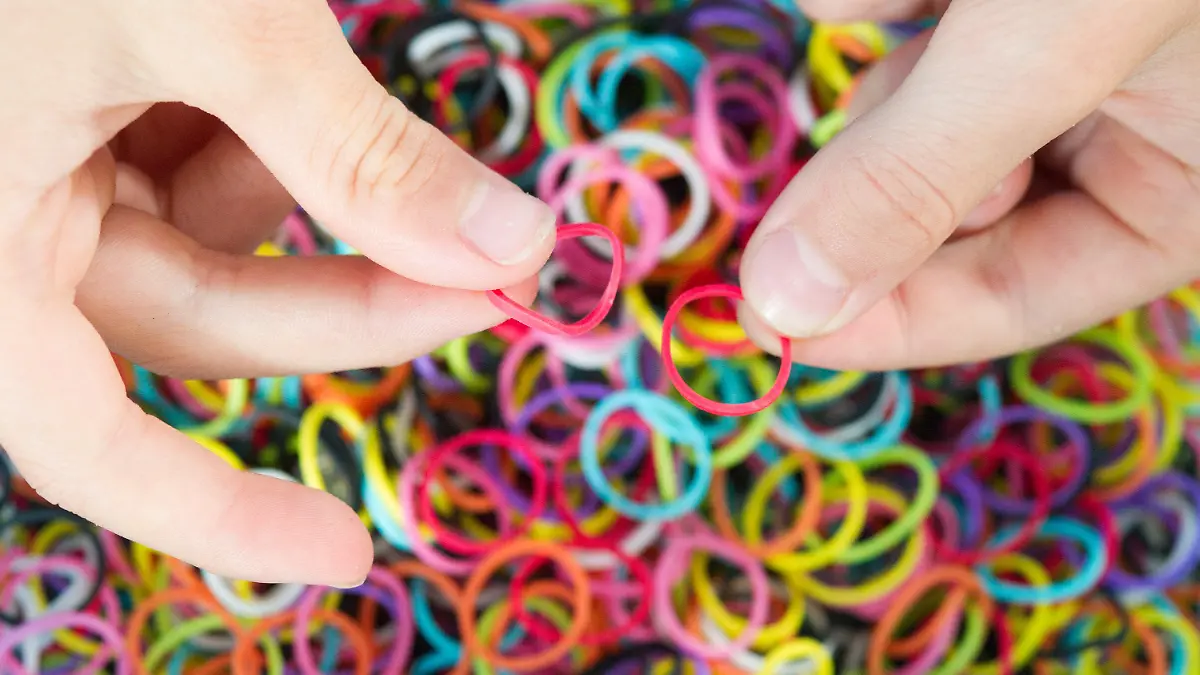 ILLUSTRATION - Ein Kind hält am 04.08.2014 in München (Bayern) Gummiringe, sogenannte Loom Bands. Das Flechten von Armbändern und anderem Schmuck aus Gummiringen - den Loom Bands - ist mittlerweile auch in Deutschland ein Trend. Foto: Tobias Hase/dpa (zu dpa «Rainbow Looms: Ein neuer Trend und seine Gefahren» vom 09.08.2014) +++(c) dpa - Bildfunk+++