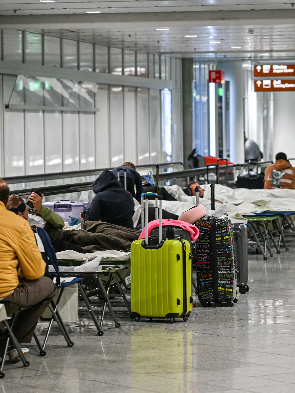 Menschen warten nach Drohnensichtungen und Flugausfällen in Flughafen München auf Feldbetten. Wegen Drohnensichtungen sind am Flughafen in München am Donnerstagabend rund 20 Flüge ausgefallen.