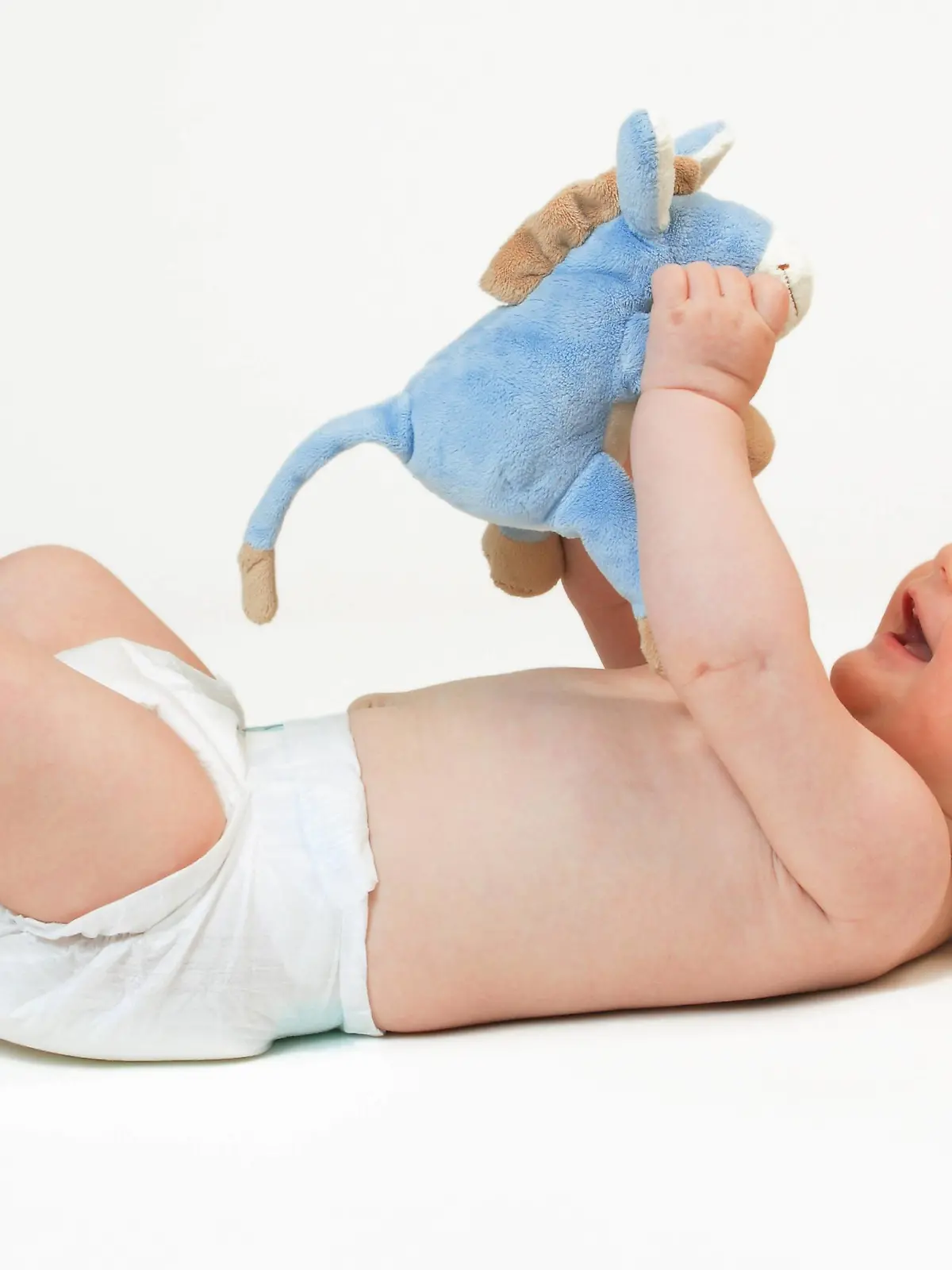 Baby auf Ruecken liegend, spielt mit Stofftier | Baby lying on back, playing with soft toy