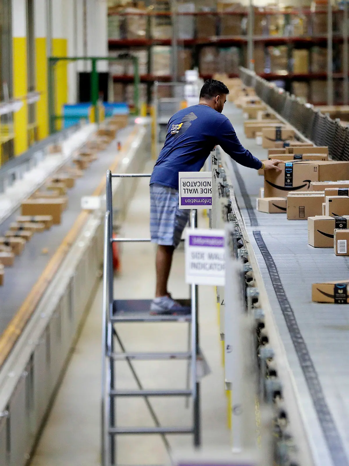 FILE - In this Tuesday, Aug. 1, 2017, photo, an Amazon employee makes sure a box riding on a belt is not sticking out at the Amazon Fulfillment center in Robbinsville Township, N.J. Amazon failed to properly record work-related injuries at warehouses located in five states, a federal agency said Friday, Dec. 16, 2022, while announcing it issued more than a dozen citations during the course of its ongoing investigation of the company. (AP Photo/Julio Cortez, File)