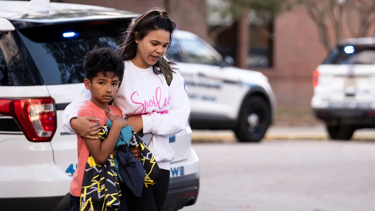 Carlos Glover, age 9, a fourth grader at Richneck Elementary School, is held by his mother Joselin Glover as they leave the school, Friday, Jan. 6, 2023 in Newport News, Va. A shooting at a Virginia elementary school sent a teacher to the hospital and ended with “an individual” in custody Friday, police and school officials in the city of Newport News said. (Billy Schuerman/The Virginian-Pilot via AP)