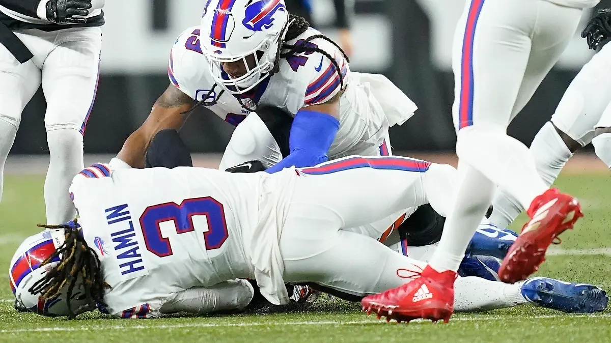Buffalo Bills safety Damar Hamlin (3) lies on the turf after making a tackle on Cincinnati Bengals wide receiver Tee Higgins, blocked from view, as Buffalo Bills linebacker Tremaine Edmunds (49) assists at the end of the play during the first half of an NFL football game between the Cincinnati Bengals and the Buffalo Bills, Monday, Jan. 2, 2023, in Cincinnati. After getting up from the play, Hamlin collapsed and was administered CPR on the field. (AP Photo/Joshua A. Bickel)