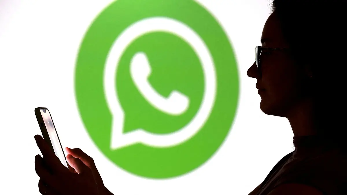 FILE PHOTO: Illustration shows a teenager posing for a photo while holding a smartphone in front of a Whatsapp logo