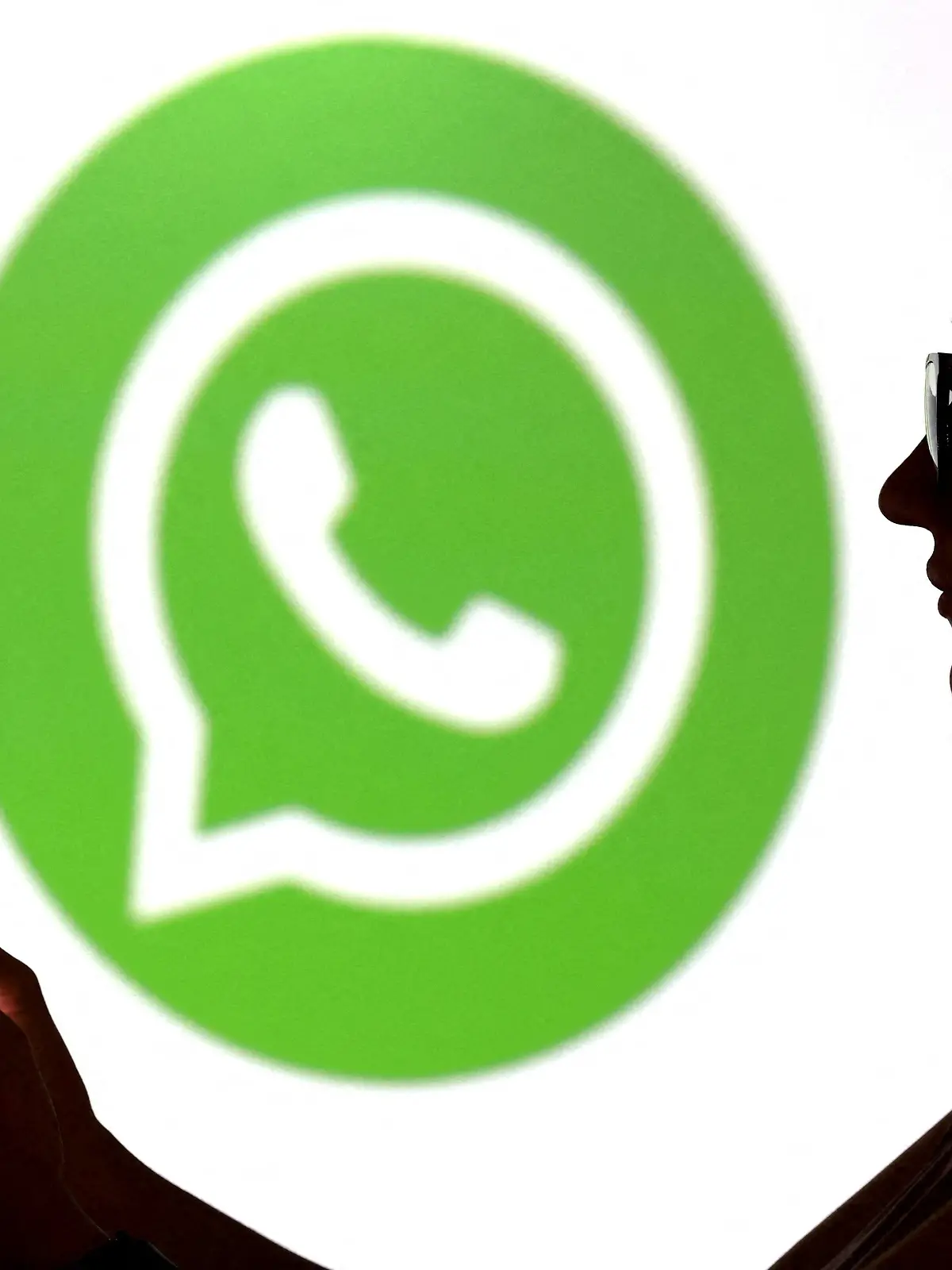 FILE PHOTO: Illustration shows a teenager posing for a photo while holding a smartphone in front of a Whatsapp logo