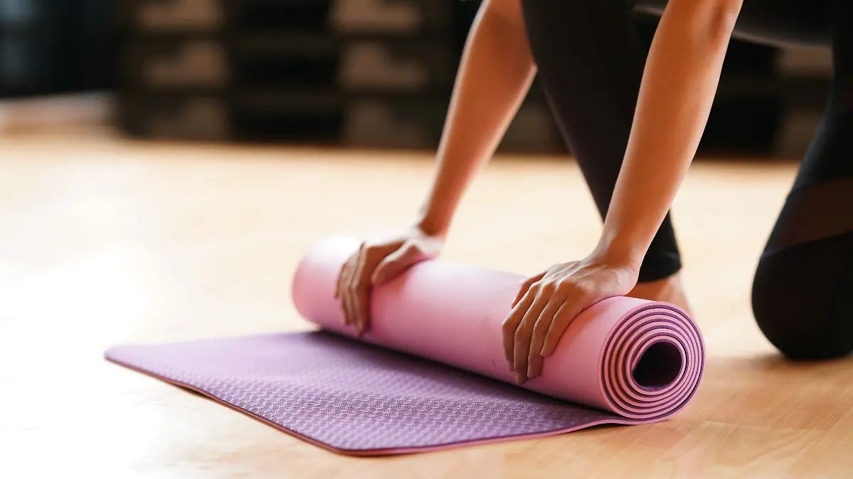 Yogamatte wird gerade eingerollt. 