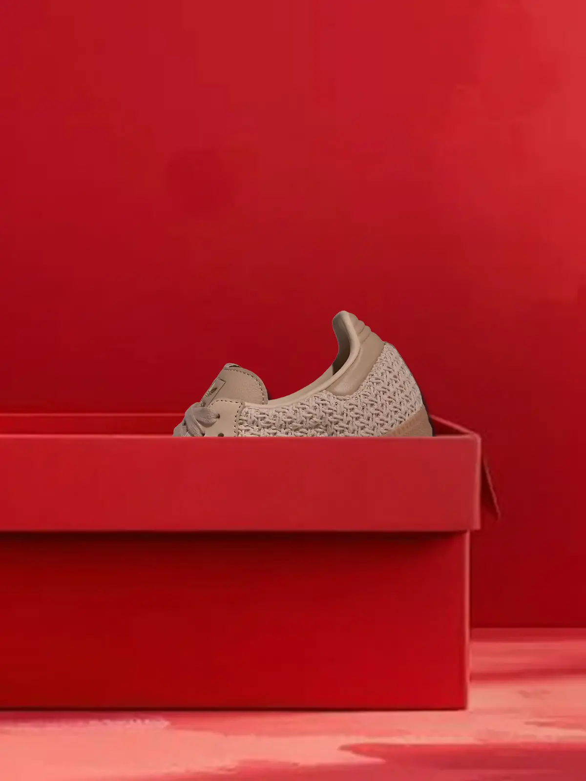 Samba-Sneaker mit Strick-Optik schaut aus einem roten Schuhkarton hervor.