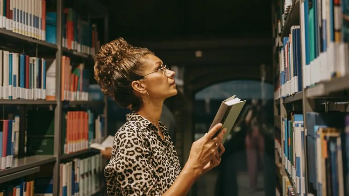 Frau stöbert in einer Bibliothek.