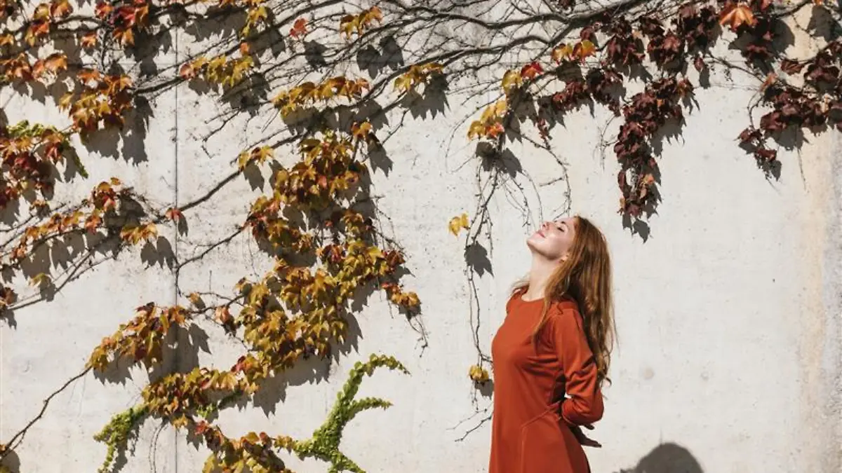 Frau trägt ein orangefarbenes Midikleid im Herbst.