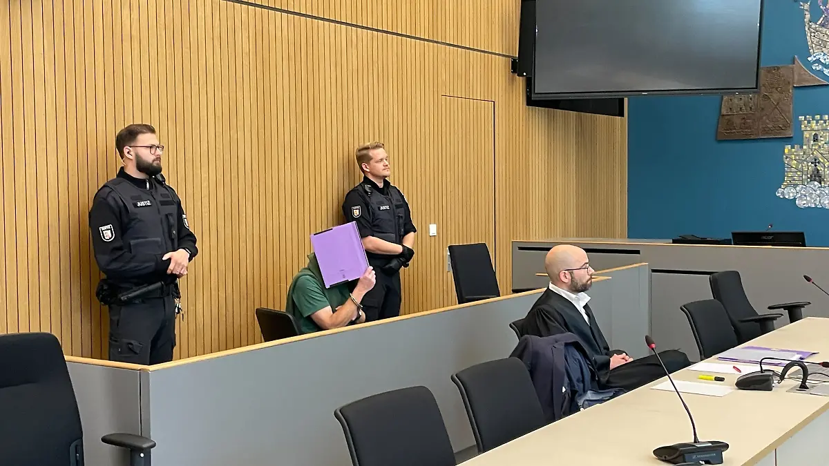 Manfred S., hier im grünen T-Shirt, verdeckt sein Gesicht am Landgericht Lübeck. Laut Staatsanwaltschaft kenne er sich am Fundort der Leiche aus.