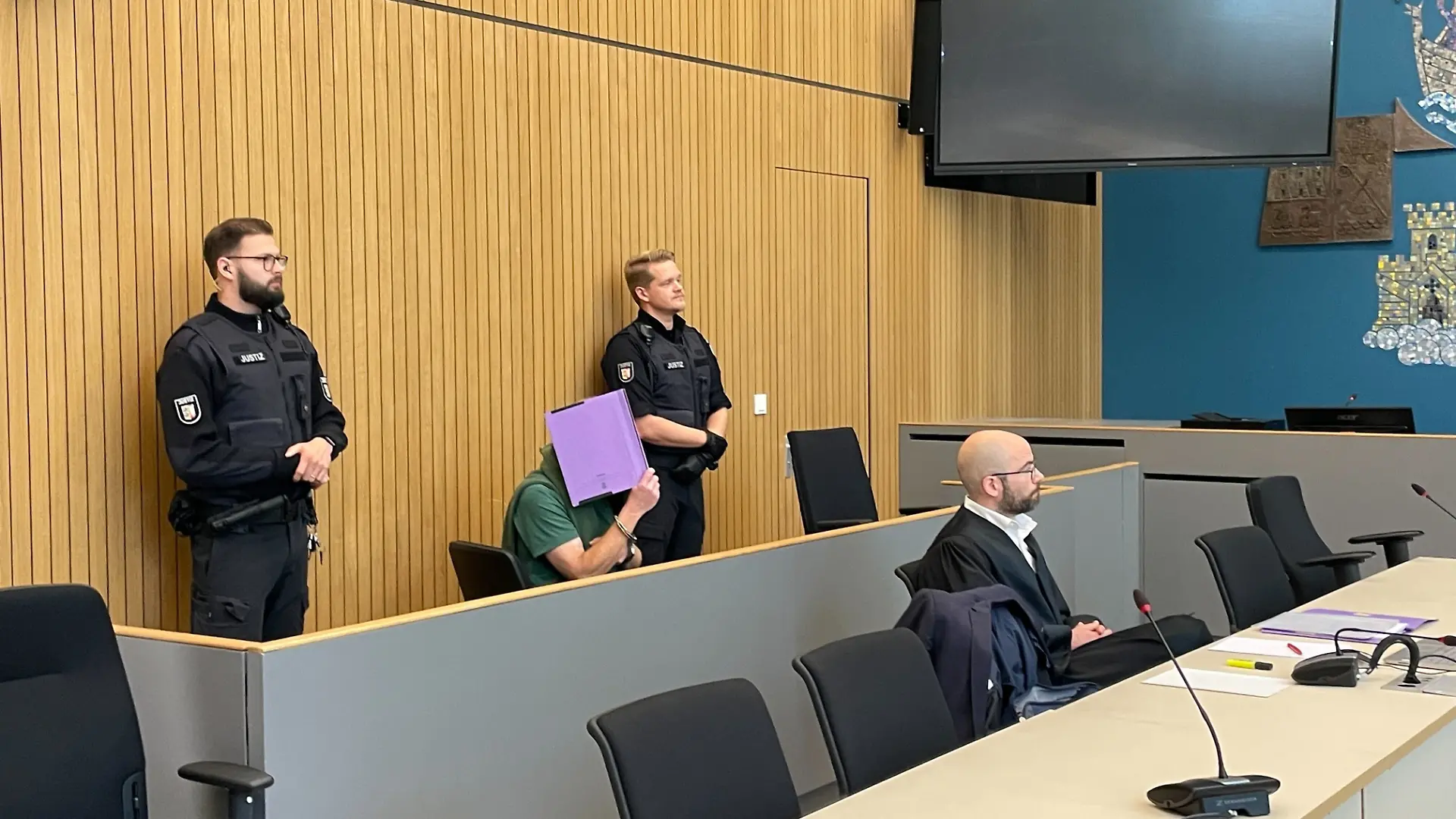 Manfred S., hier im grünen T-Shirt, verdeckt sein Gesicht am Landgericht Lübeck. Laut Staatsanwaltschaft kenne er sich am Fundort der Leiche aus.