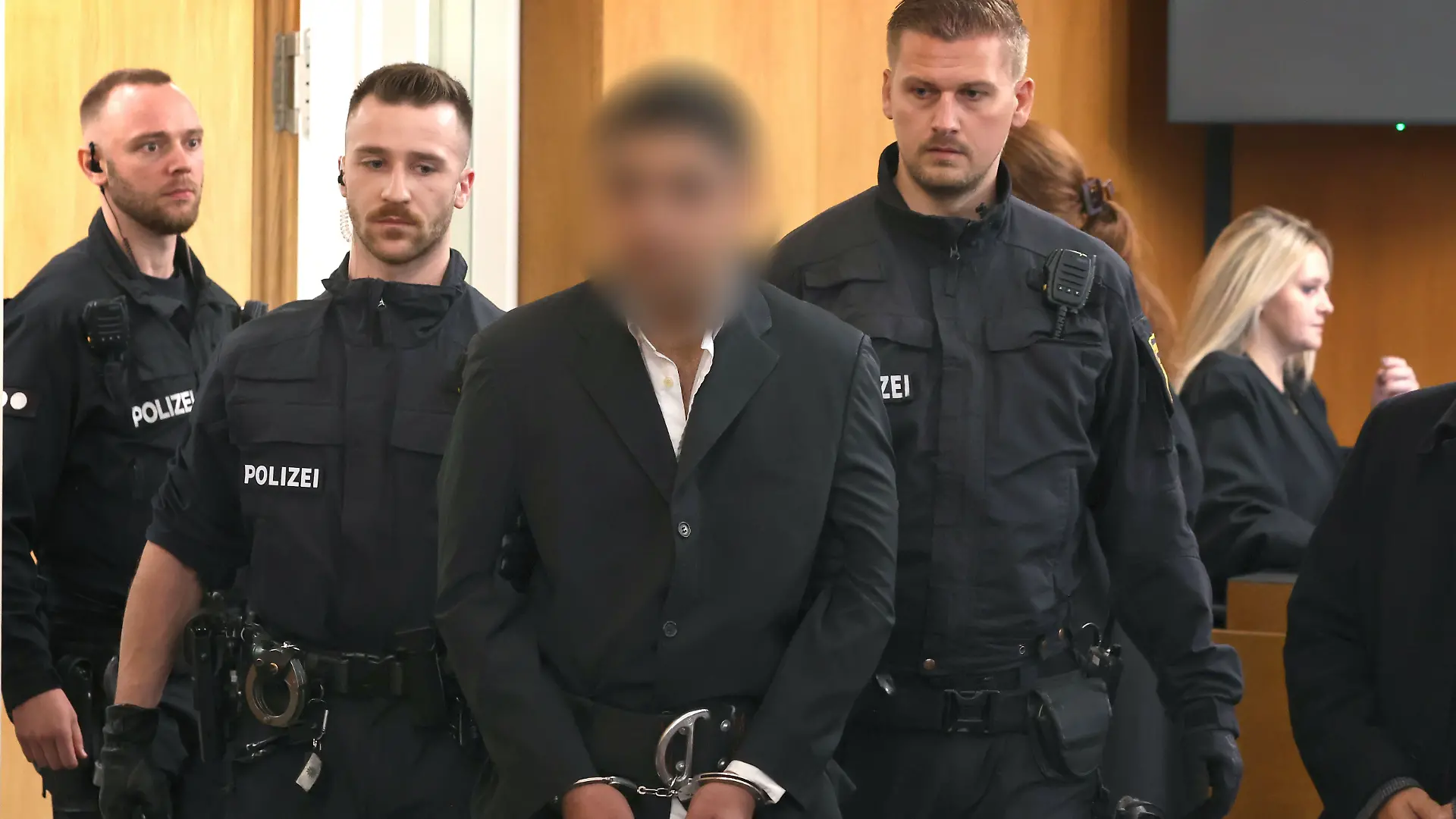 Ein Beschuldigter (3.v.l) wird von Polizisten in einen Gerichtssaal des Landgerichtes geführt. Der Afghane soll am 22. Januar einen 2-jährigen Jungen und einen 41-Jährigen mit einem Messer getötet haben. Drei Menschen wurden schwer verletzt. 