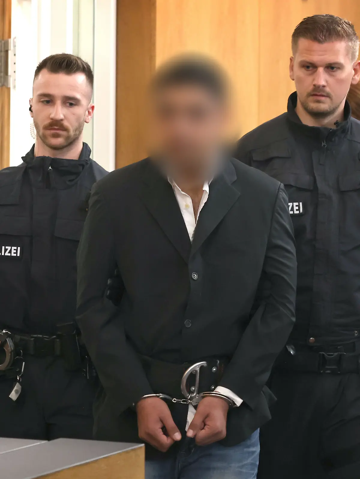 Ein Beschuldigter (3.v.l) wird von Polizisten in einen Gerichtssaal des Landgerichtes geführt. Der Afghane soll am 22. Januar einen 2-jährigen Jungen und einen 41-Jährigen mit einem Messer getötet haben. Drei Menschen wurden schwer verletzt. 