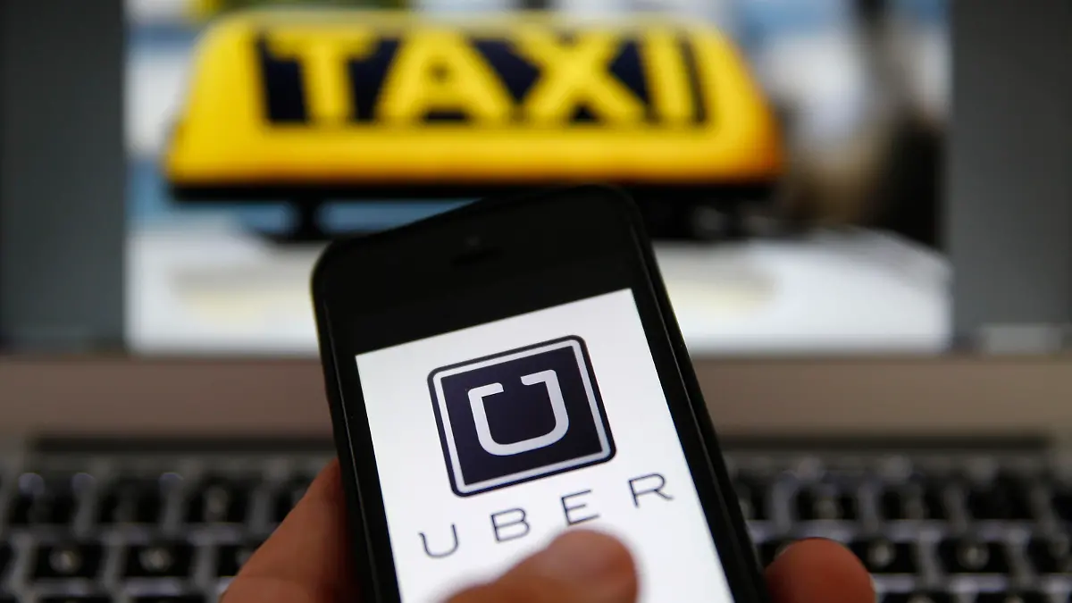 An illustration picture shows the logo of car-sharing service app Uber on a smartphone next to the picture of an official German taxi sign in Frankfurt, September 15, 2014. A Frankfurt high court will hold a hearing on a recent lawsuit brought against Uberpop by Taxi Deutschland on Tuesday.  San Francisco-based Uber, which allows users to summon taxi-like services on their smartphones, offers two main services, Uber, its classic low-cost, limousine pick-up service, and Uberpop, a newer ride-sharing service, which connects private drivers to passengers - an established practice in Germany that nonetheless operates in a legal grey area of rules governing commercial transportation. The company has faced regulatory scrutiny and court injunctions from its early days, even as it has expanded rapidly into roughly 150 cities around the world.   REUTERS/Kai Pfaffenbach (GERMANY - Tags: BUSINESS EMPLOYMENT CRIME LAW TRANSPORT)
