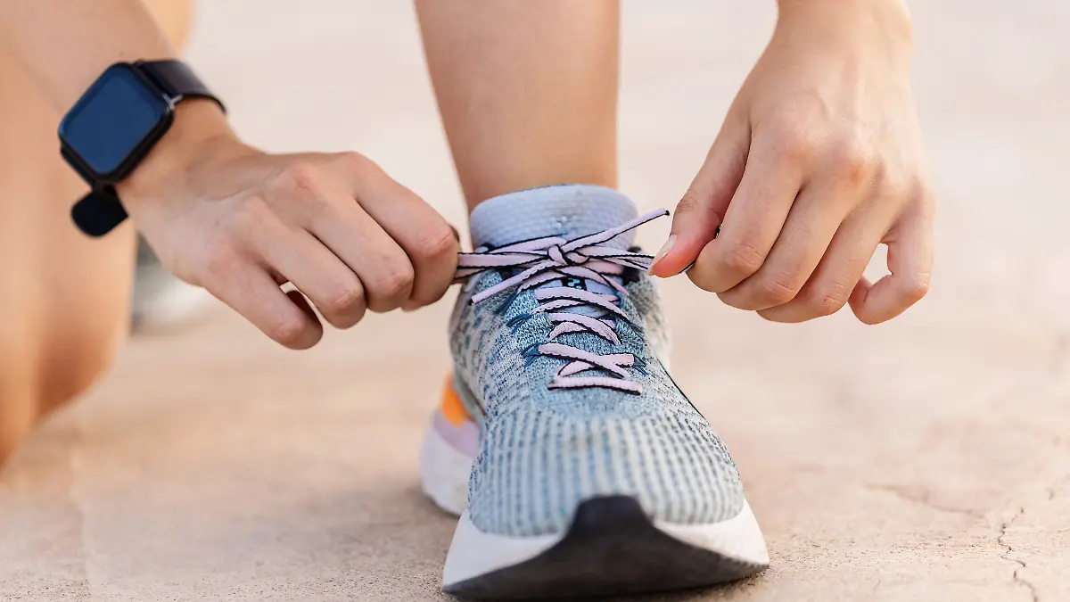 Frau schnürt ihre Laufschuhe zu. 