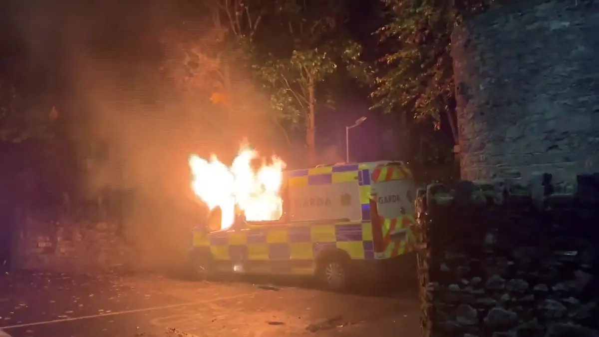 Ein irisches Polizeiauto steht bei dem Protest vor einer Flüchtlingsunterkunft in Flammen