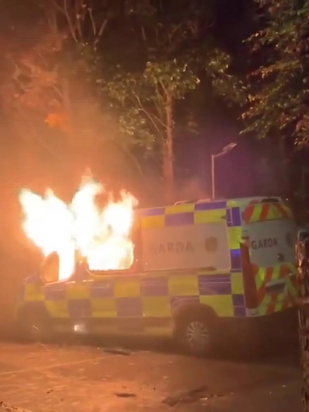 Ein irisches Polizeiauto steht bei dem Protest vor einer Flüchtlingsunterkunft in Flammen