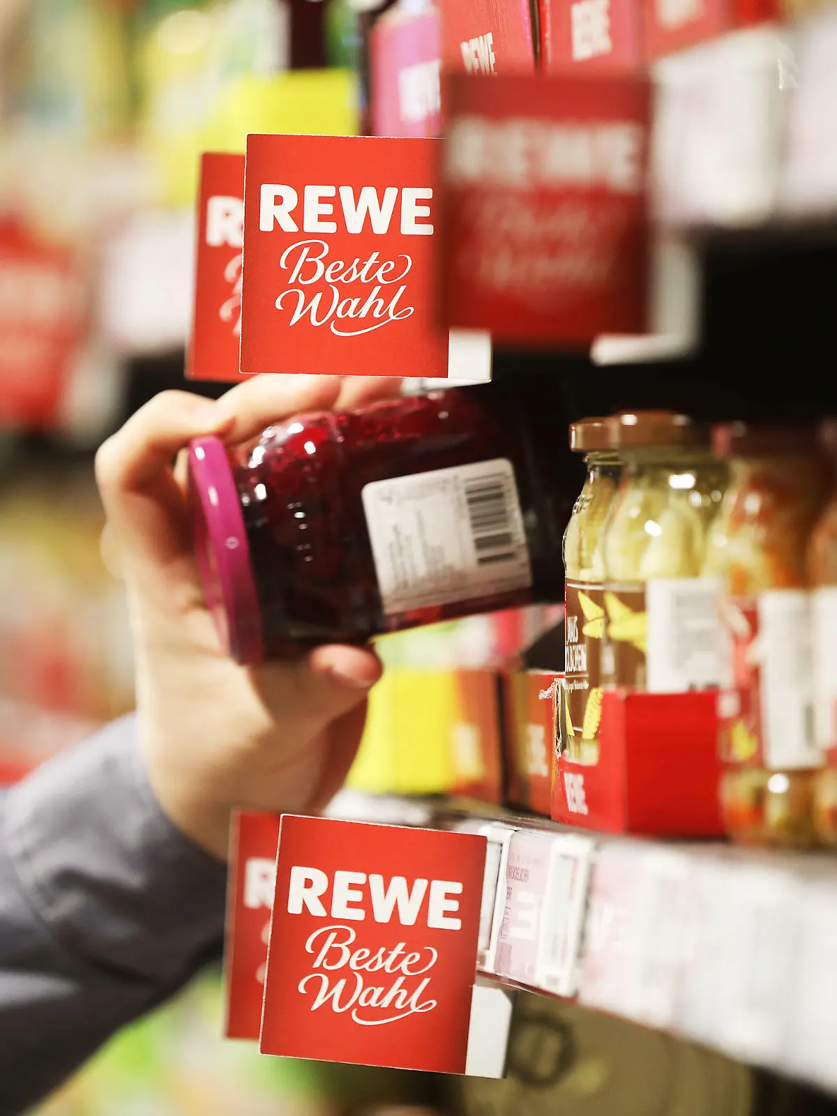 ARCHIV - 15.04.2021, Nordrhein-Westfalen, Köln: Ein Mann nimmt in einem Supermarkt ein Glas aus dem Regal. (zu dpa "Rewe: Markenartikler fordern Preisanhebungen in Milliardenhöhe") Foto: Oliver Berg/dpa +++ dpa-Bildfunk +++