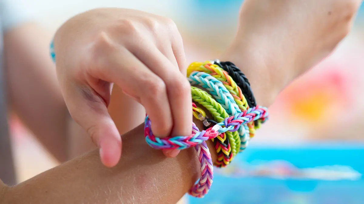 ILLUSTRATION - Ein Mädchen streift sich am 04.08.2014 in München (Bayern) ein Fischgrätenarmband aus Loom Bands über ihr Handgelenk. Das Flechten von Armbändern und anderem Schmuck aus Gummiringen - den Loom Bands - ist mittlerweile auch in Deutschland ein Trend. Foto: Tobias Hase/dpa (zu dpa «Rainbow Looms: Ein neuer Trend und seine Gefahren» vom 09.08.2014) +++(c) dpa - Bildfunk+++