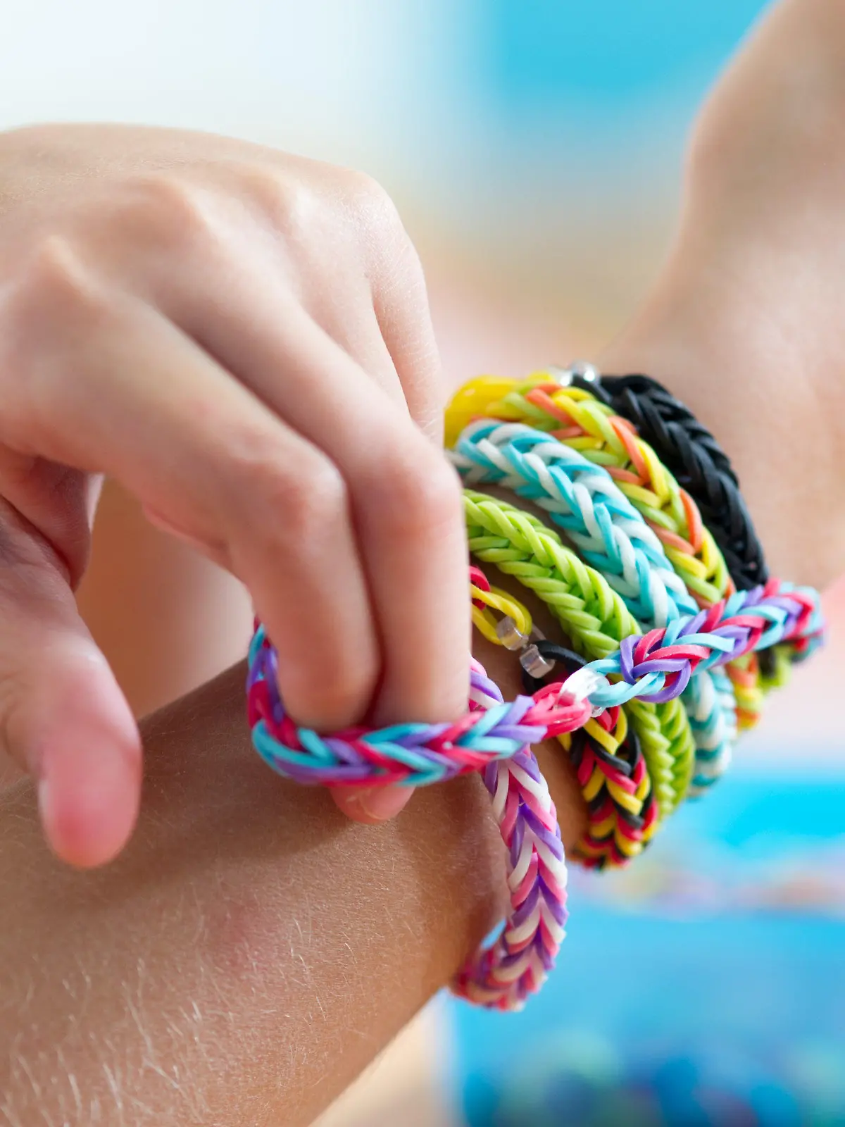 ILLUSTRATION - Ein Mädchen streift sich am 04.08.2014 in München (Bayern) ein Fischgrätenarmband aus Loom Bands über ihr Handgelenk. Das Flechten von Armbändern und anderem Schmuck aus Gummiringen - den Loom Bands - ist mittlerweile auch in Deutschland ein Trend. Foto: Tobias Hase/dpa (zu dpa «Rainbow Looms: Ein neuer Trend und seine Gefahren» vom 09.08.2014) +++(c) dpa - Bildfunk+++