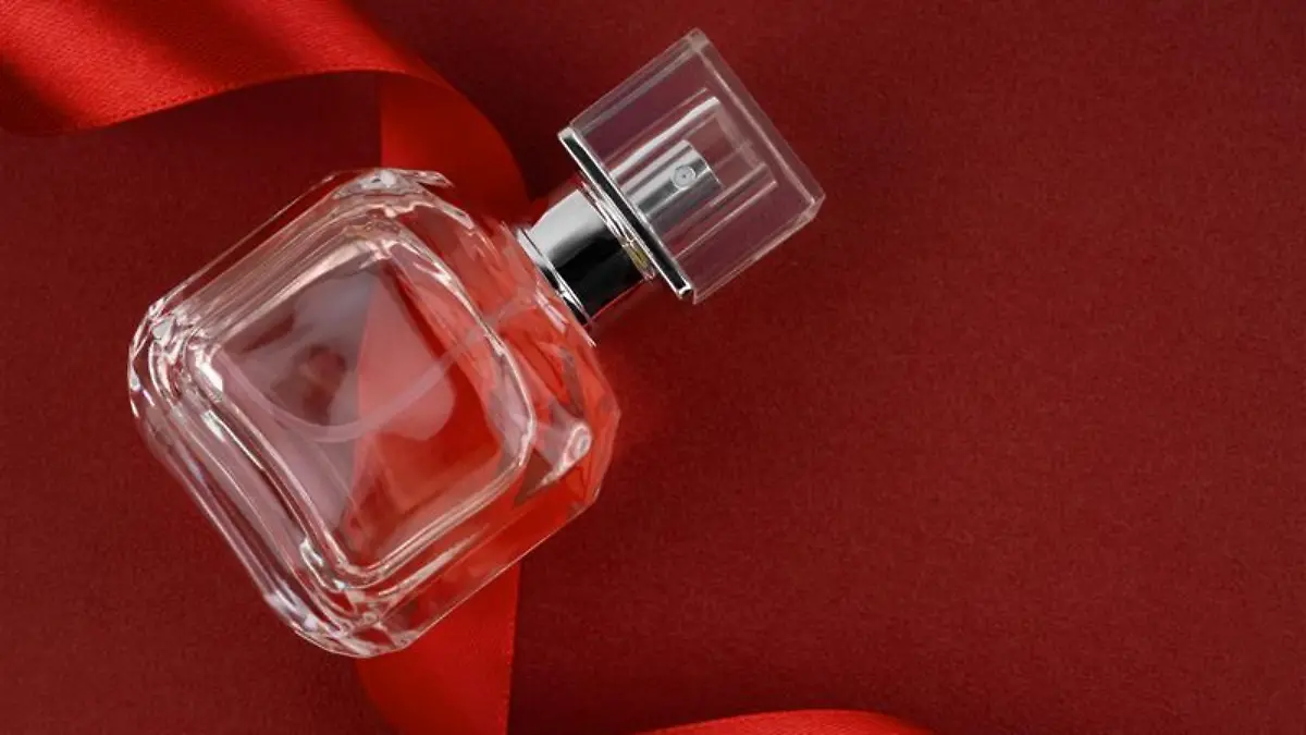 Parfumflakon vor rotem Hintergrund.
