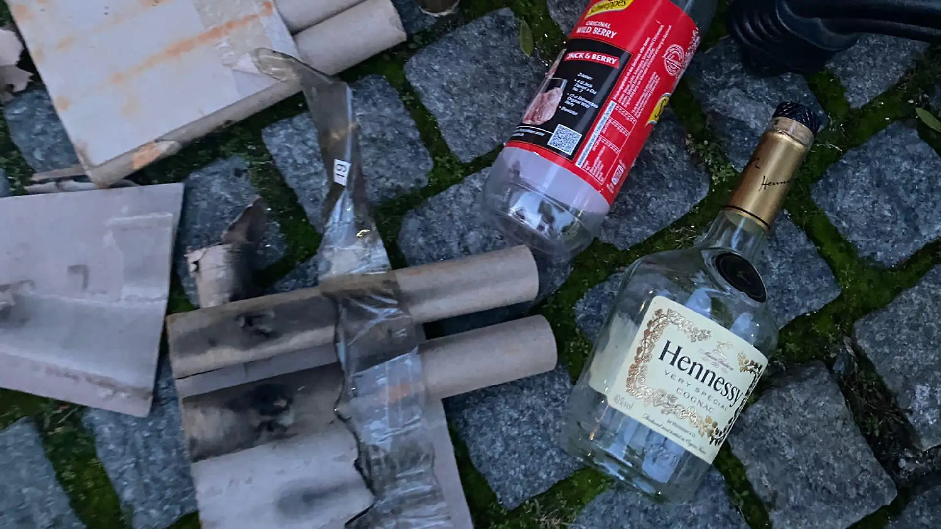 Glasscherben, leere Flaschen und Böller liegen quer verteilt auf dem Boden.