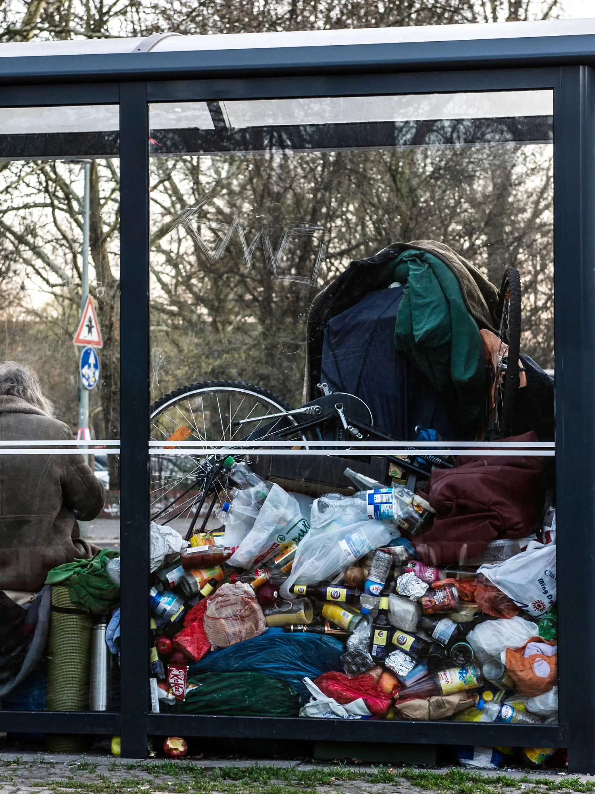 Ein Mann sitzt am 13.03.2014 in Berlin mit seinem Hab und Gut in einem Bus-Wartehäuschen an der Reichenberger Straße. Der Obdachlose wohnt seit mehreren Monaten in der Haltestelle, an der momentan keine Busse halten. Foto: Paul Zinken/dpa (zu dpa «Ex-Ingenieur wohnt in Berliner Bushaltestelle» vom 14.03.2014)