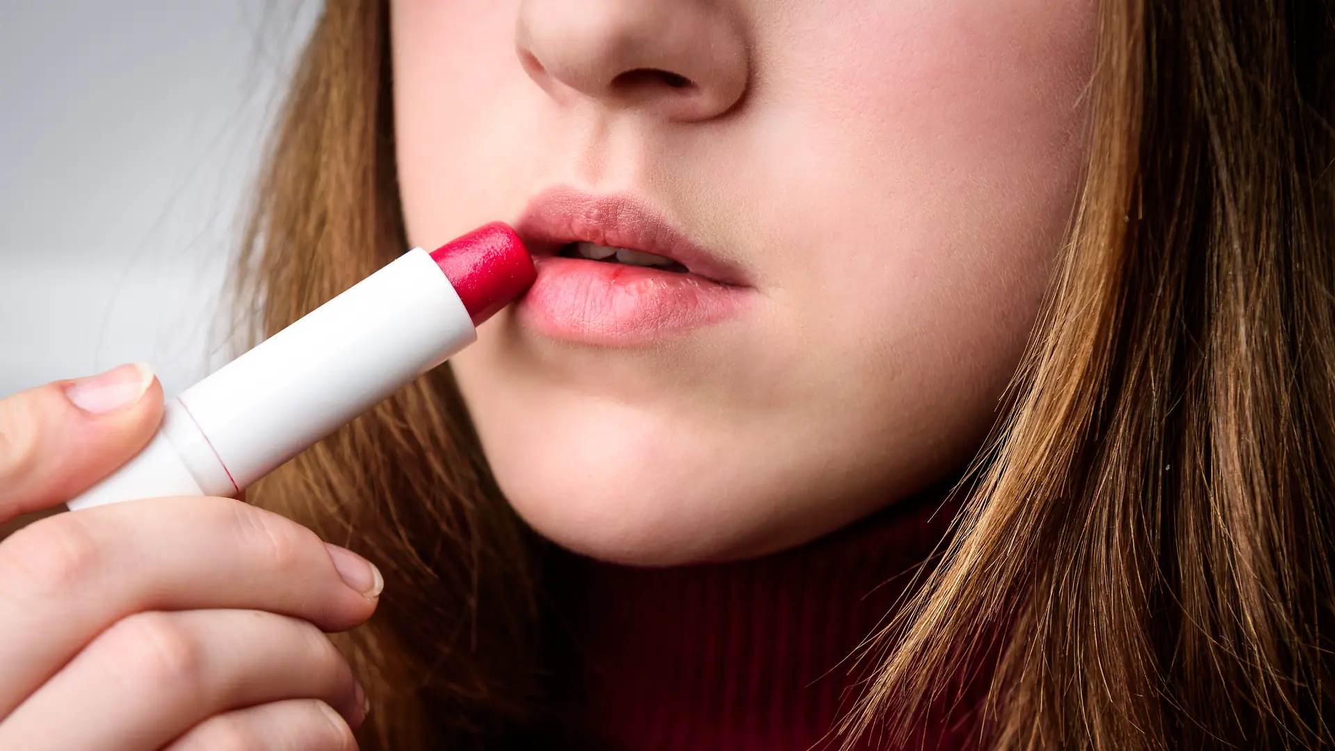 Junge Frau benutzt Lippenpflegebalsam mit Farbe