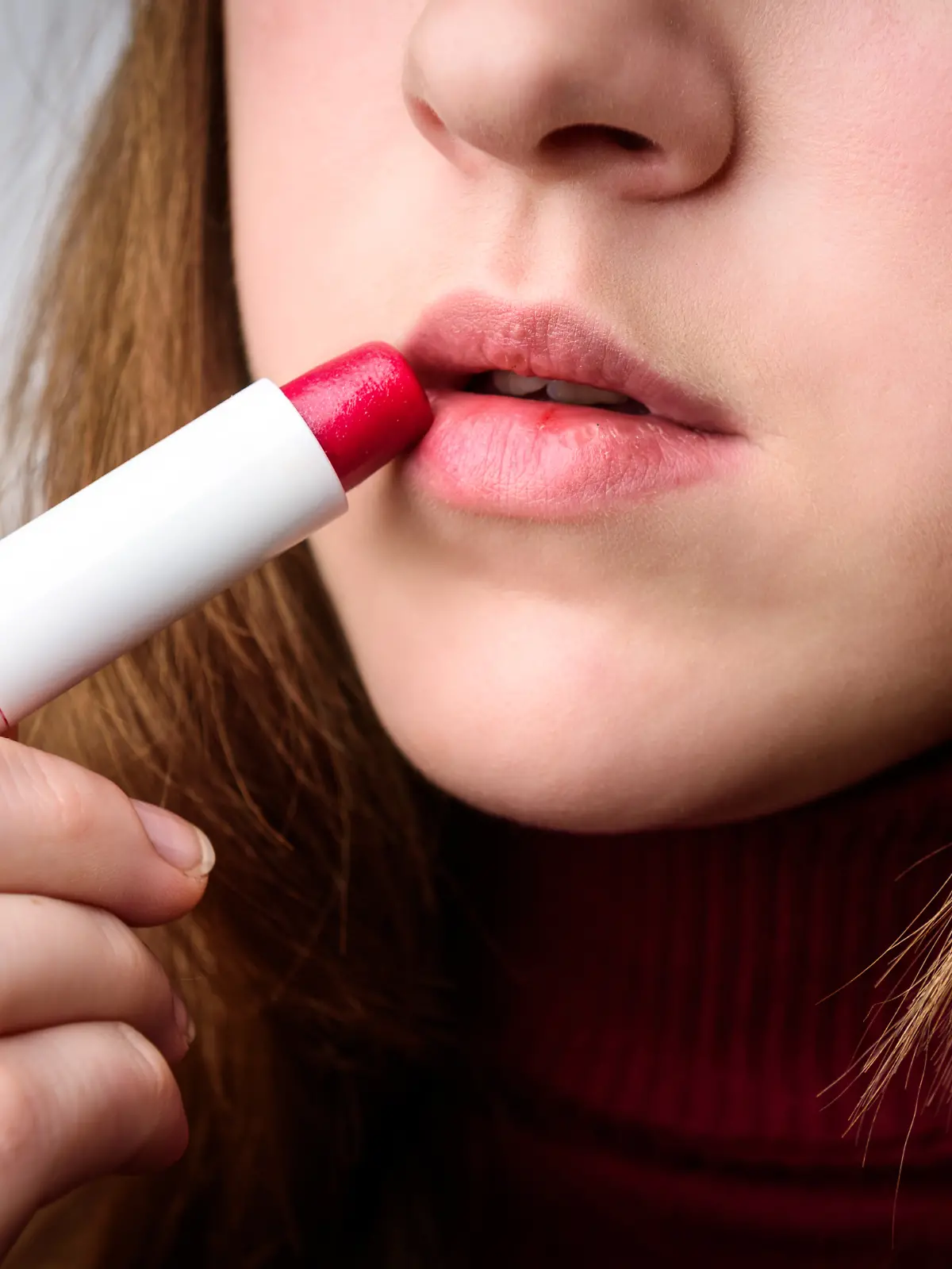 Junge Frau benutzt Lippenpflegebalsam mit Farbe