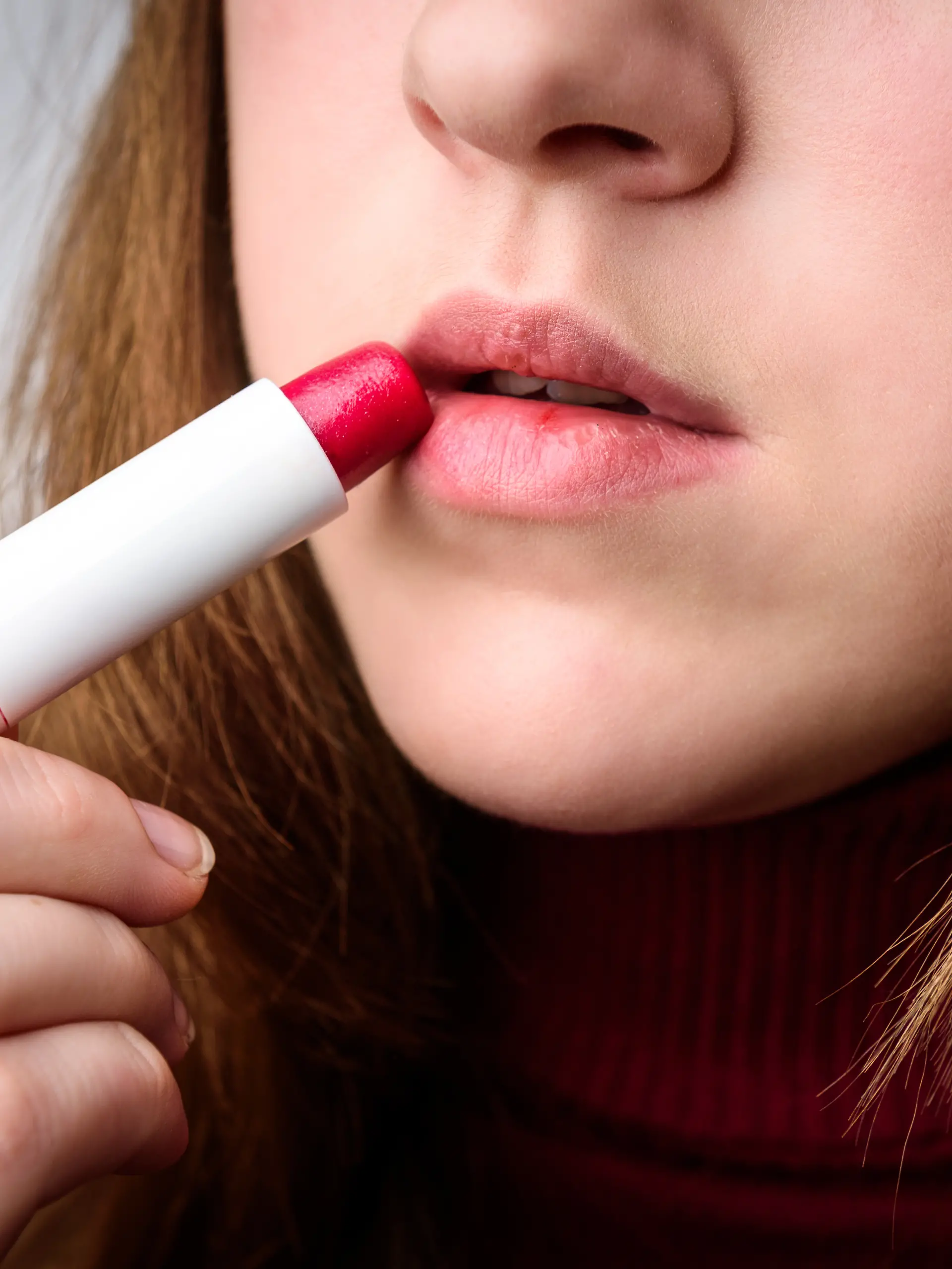 Junge Frau benutzt Lippenpflegebalsam mit Farbe