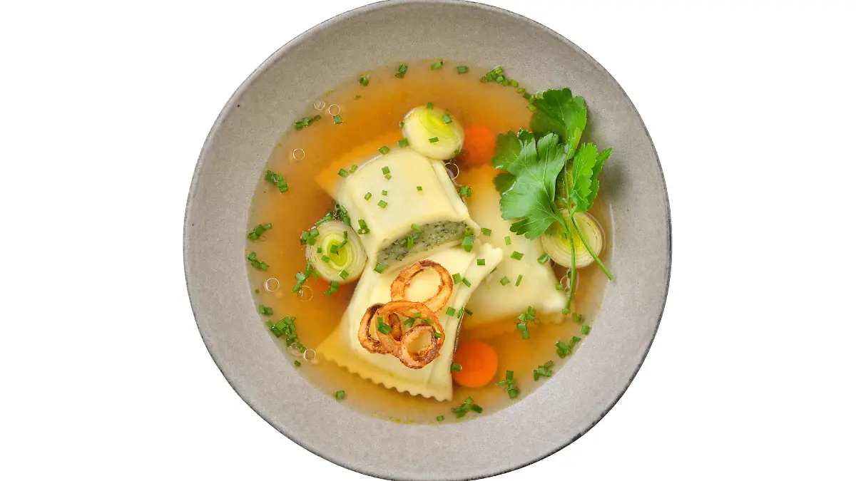 Kräftige Maultaschensuppe mit Röstzwiebeln im Keramikteller auf weißem Hintergrund