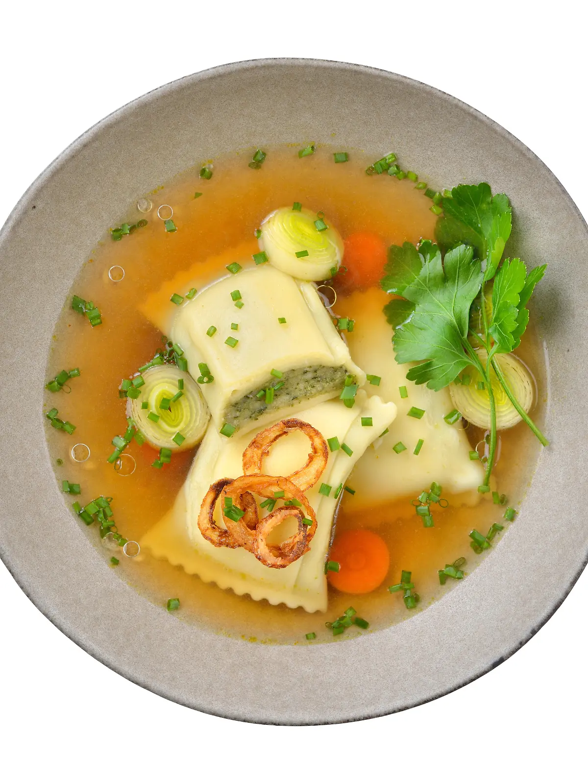 Kräftige Maultaschensuppe mit Röstzwiebeln im Keramikteller auf weißem Hintergrund