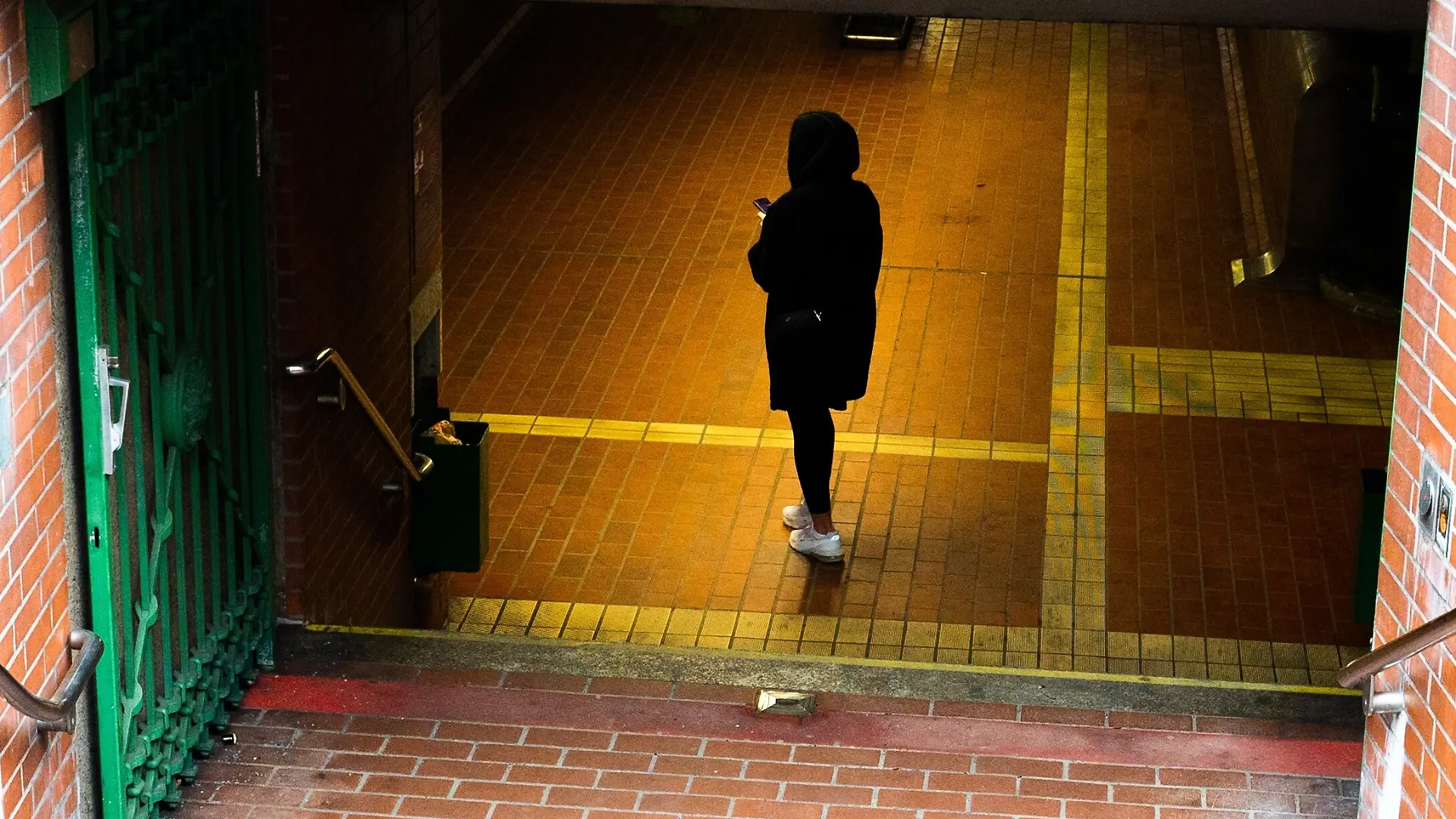 Eine Frau steht in einem schlecht beleuchteten U-Bahn-Eingang (Symboleingang) 