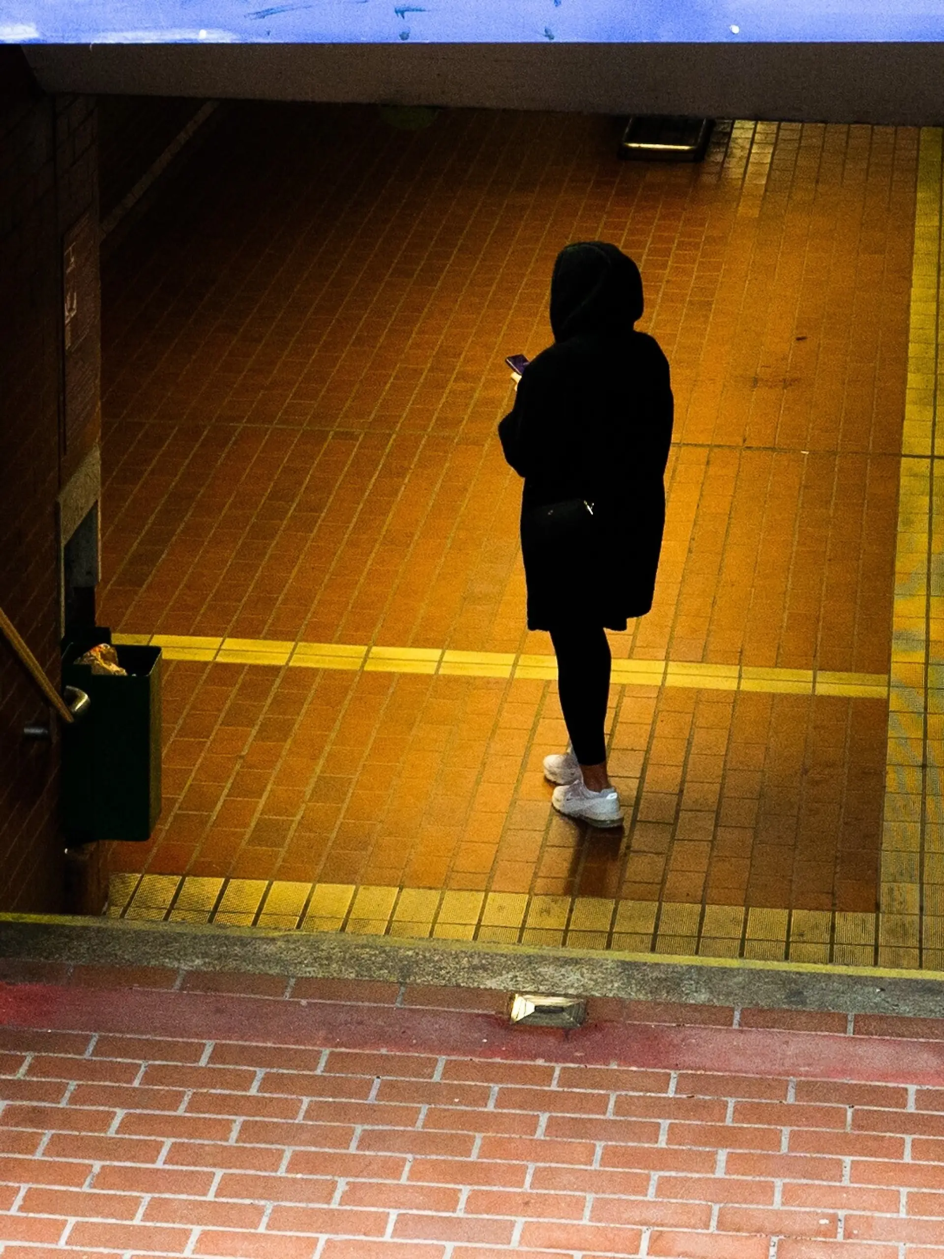 Eine Frau steht in einem schlecht beleuchteten U-Bahn-Eingang (Symboleingang) 