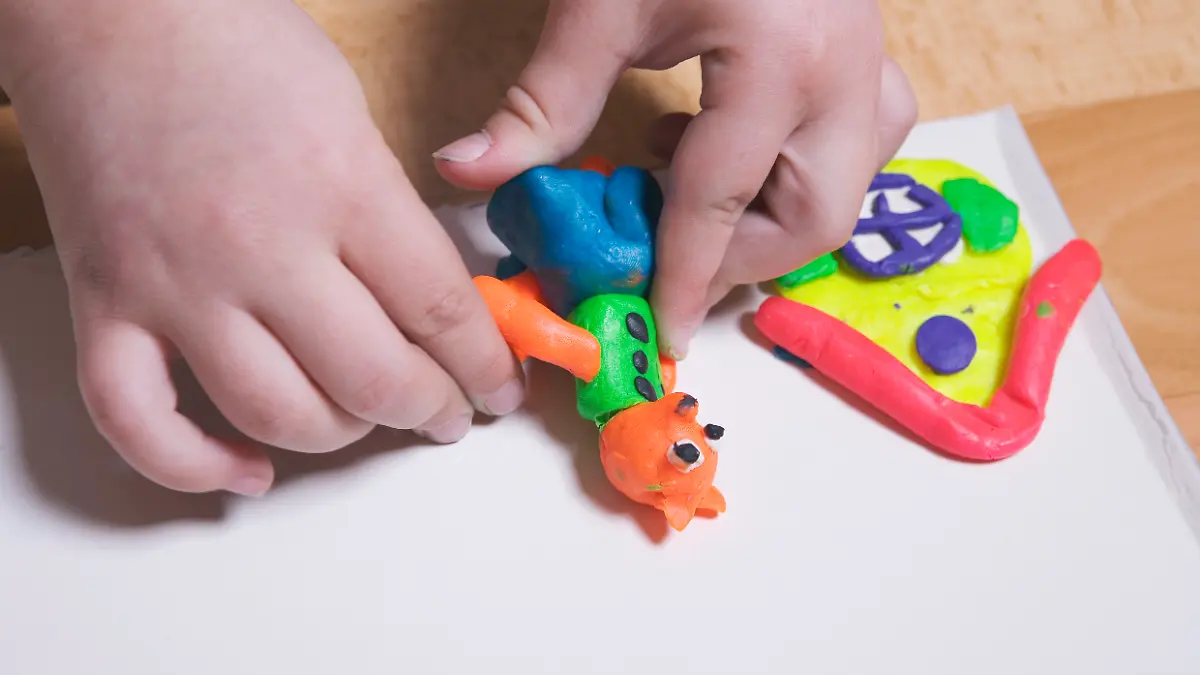 Kinderhände, die mit bunter Knetmasse spielen