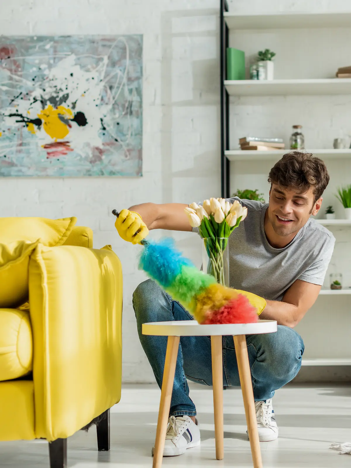 Mann und Frau sind im Wohnzimmer ihrer Wohnung und putzen den Boden sowie den Beistelltisch.