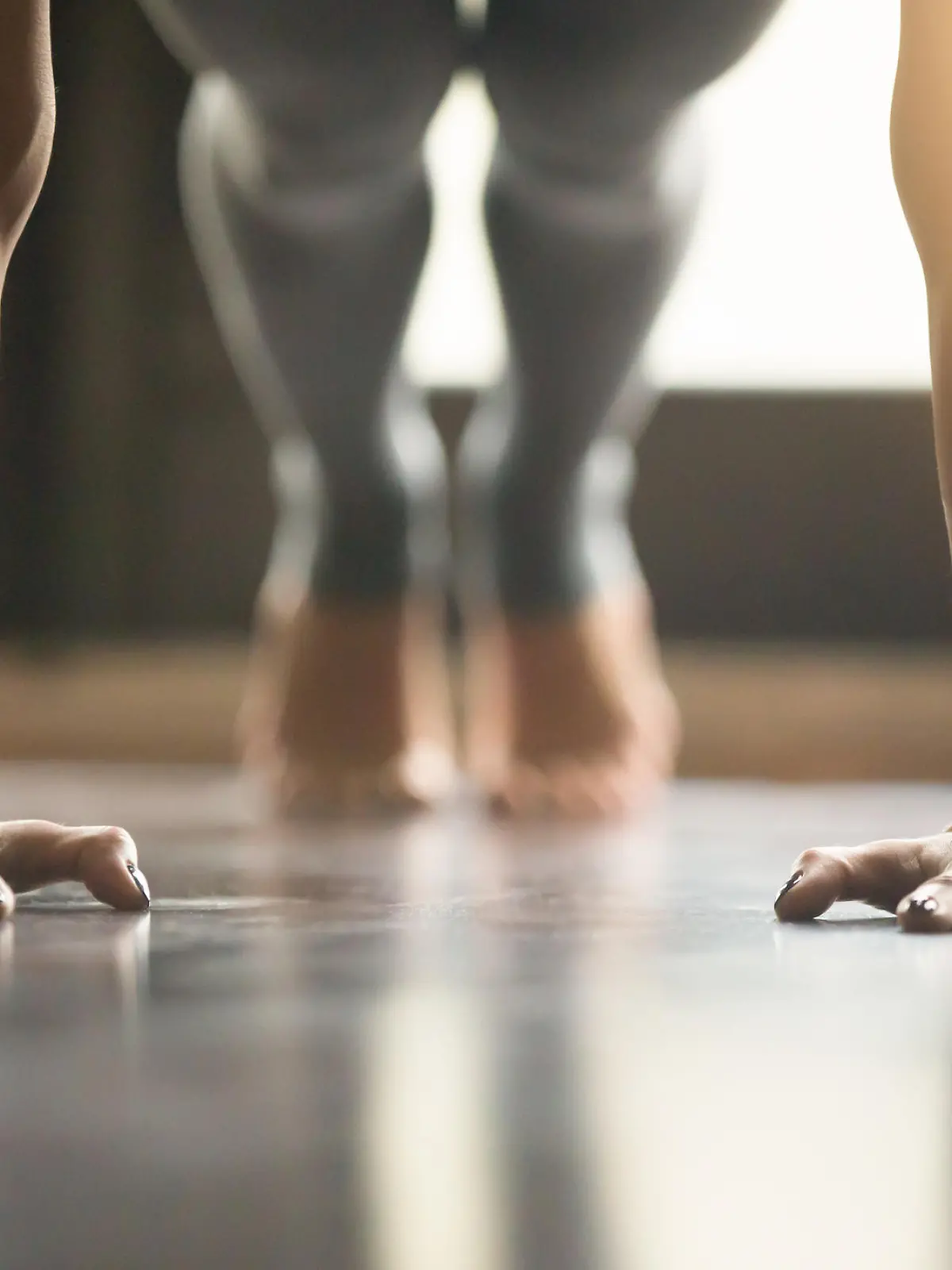 Young woman practicing yoga, doing Push ups or press ups exercise, phalankasana Plank pose, working out, wearing sportswear, grey pants, indoor, home interior, living room floor. Close-up of hands