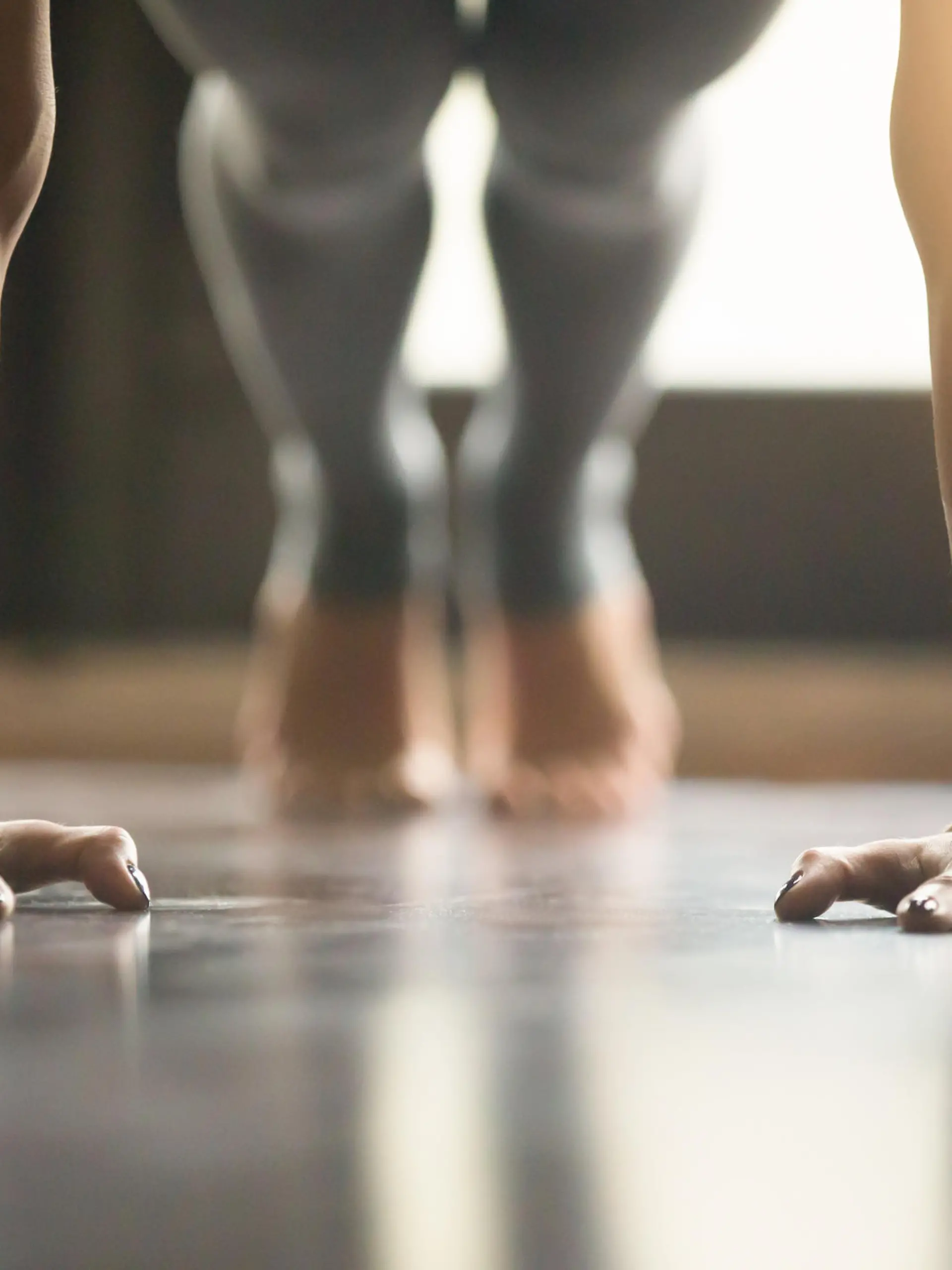 Young woman practicing yoga, doing Push ups or press ups exercise, phalankasana Plank pose, working out, wearing sportswear, grey pants, indoor, home interior, living room floor. Close-up of hands