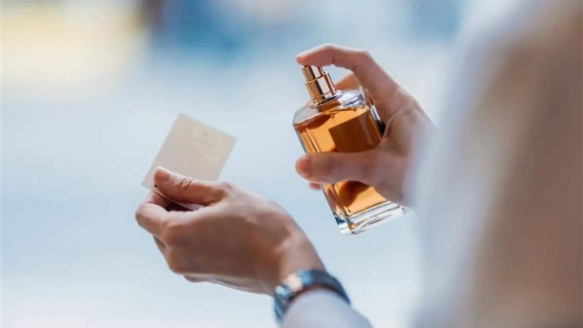 Person sprüht Parfum.