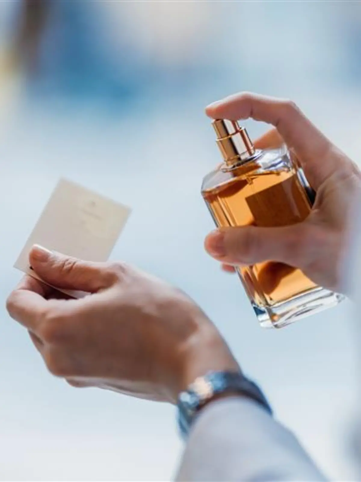 Person sprüht Parfum.