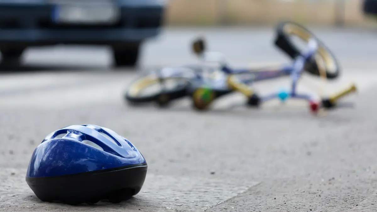 Ein Kinderrad und ein Fahrradhelm liegen auf einer Straße