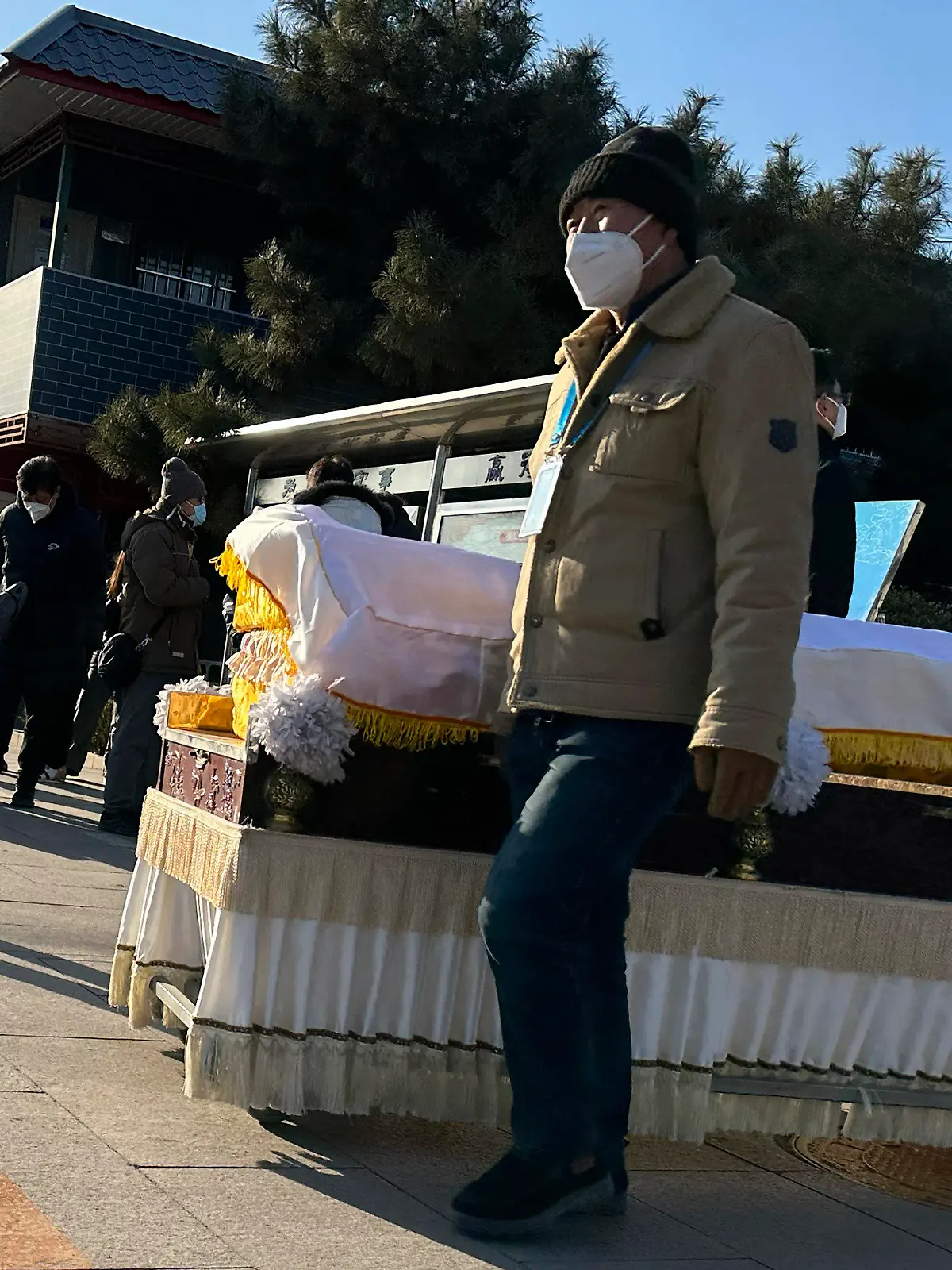 31.12.2022, China, Beijing: Arbeiter schieben einen Sarg vor ein Krematorium. China hat Anfang dieses Monats viele seiner strengen Corona-Beschränkungen aufgehoben, so dass sich das Virus rasch ausbreiten konnte. Die Zahl der Einäscherungen ist um ein Vielfaches gestiegen. Viele Bestattungsinstitute sind ausgelastet und bitten die Familien die Beerdigungen zu verschieben. Foto: Ng Han Guan/AP/dpa +++ dpa-Bildfunk +++