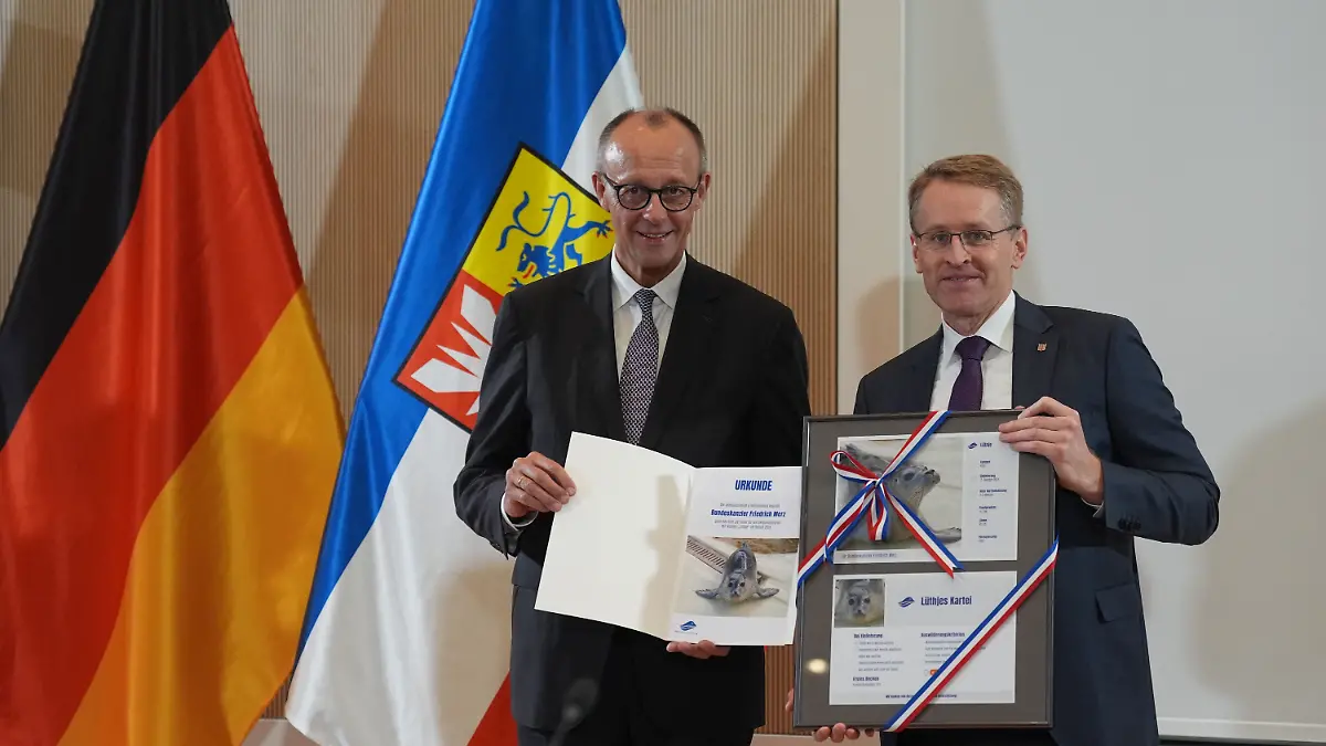 Bundeskanzler Friedrich Merz (CDU) erhält von Schleswig-Holsteins Ministerpräsident Daniel Günther (CDU) im Rathaus von Husum eine Urkunde für die Patenschaft der Robbe „Lütje” in der Seehundstation Friedrichskoog. 