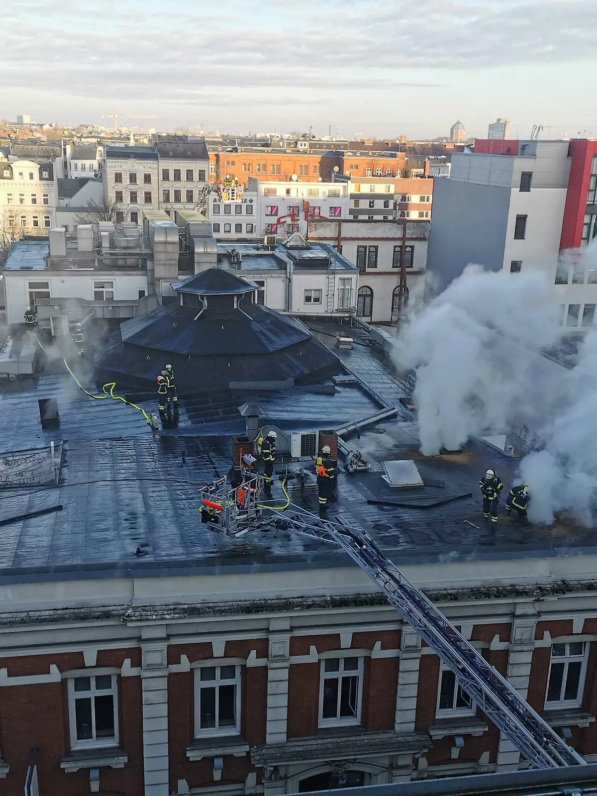 03.01.2023, Hamburg: Rauch steigt über dem Dach eines Theatergebäudes auf der Reeperbahn auf. Zwei Löschzüge seien im Einsatz, um den Brand zu bekämpfen, teilte die Feuerwehr auf Twitter mit. Betroffen sei ein Hintergebäude von Schmidts Tivoli.(zu dpa: «Brand an Theatergebäude auf St. Pauli - Feuerwehr im Einsatz») Foto: Steve Hutchings/TNN/dpa +++ dpa-Bildfunk +++