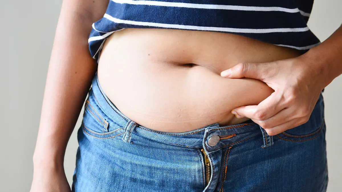 Frau mit Bauchfett in zu enger Jeans