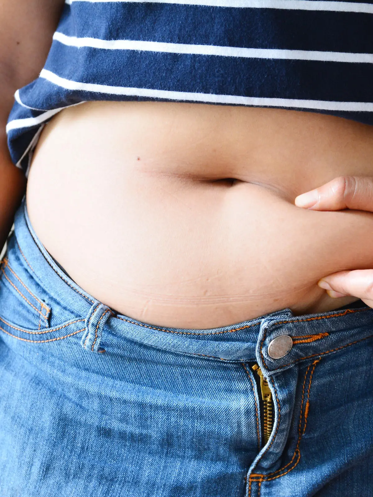 Frau mit Bauchfett in zu enger Jeans