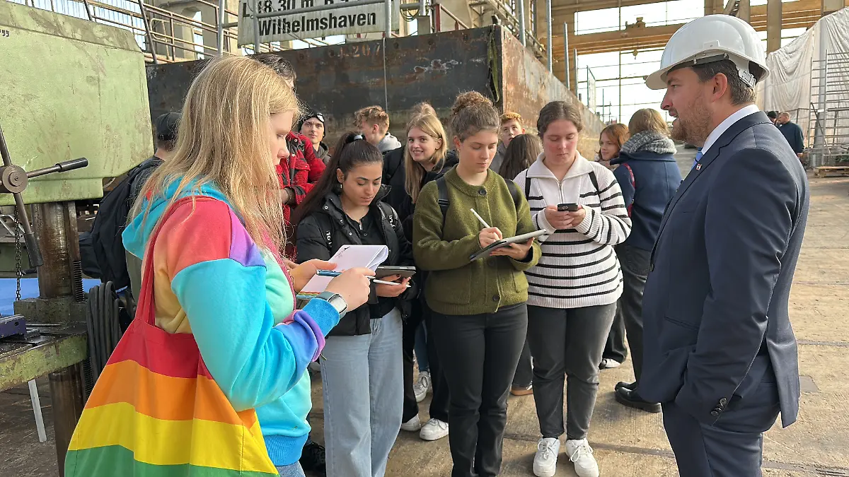 Im Gespräch mit dem Hitzler-Werft Geschäftsführer Kai Klimenko notiert die Schulklasse Informationen für den Beitrag.