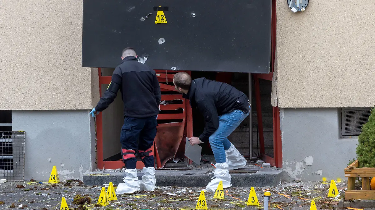 Die Kriminalpolizei sichert die Spuren einer Explosion an der Eingangstür eines Wohnhauses.